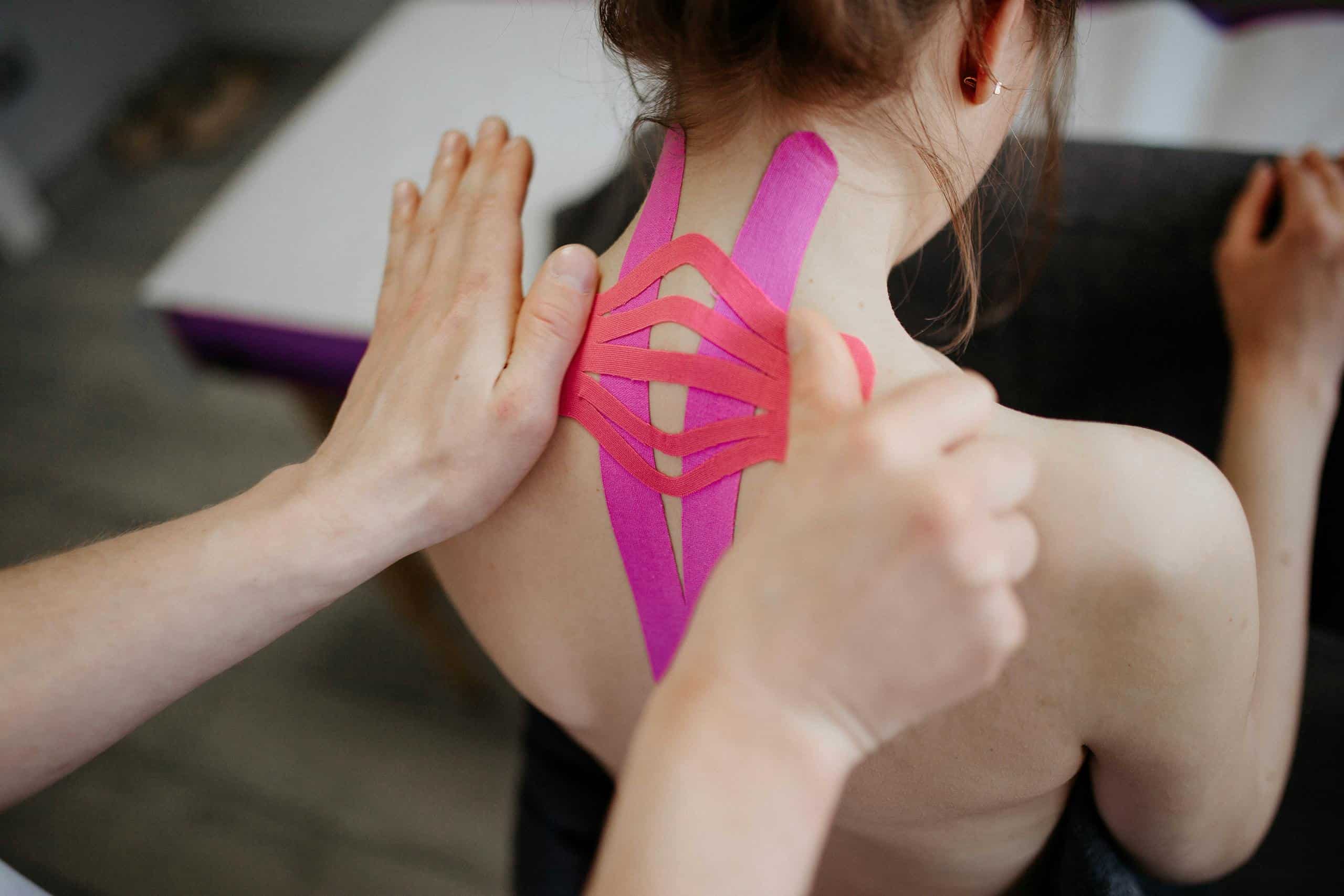 A close-up image of kinesio tape being applied to a person's back, showcasing injury rehabilitation.