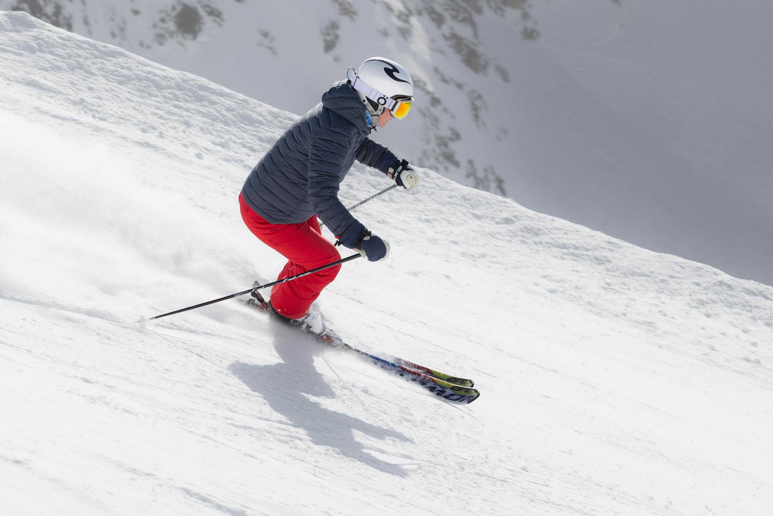 A skier in red pants navigates a snowy mountain slope on a bright winter day.