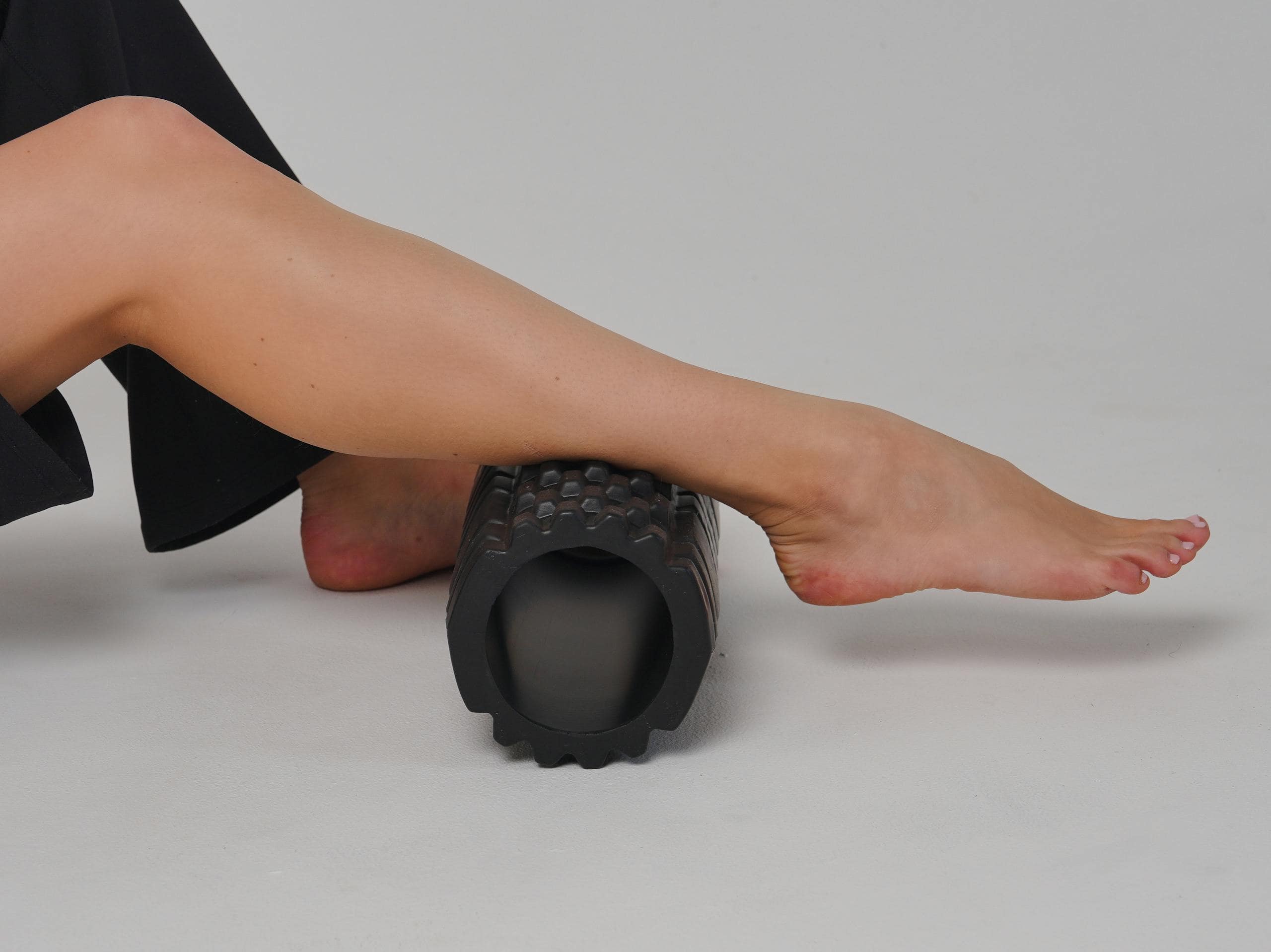 Close-up of a leg using a foam roller for stretching and muscle relief.