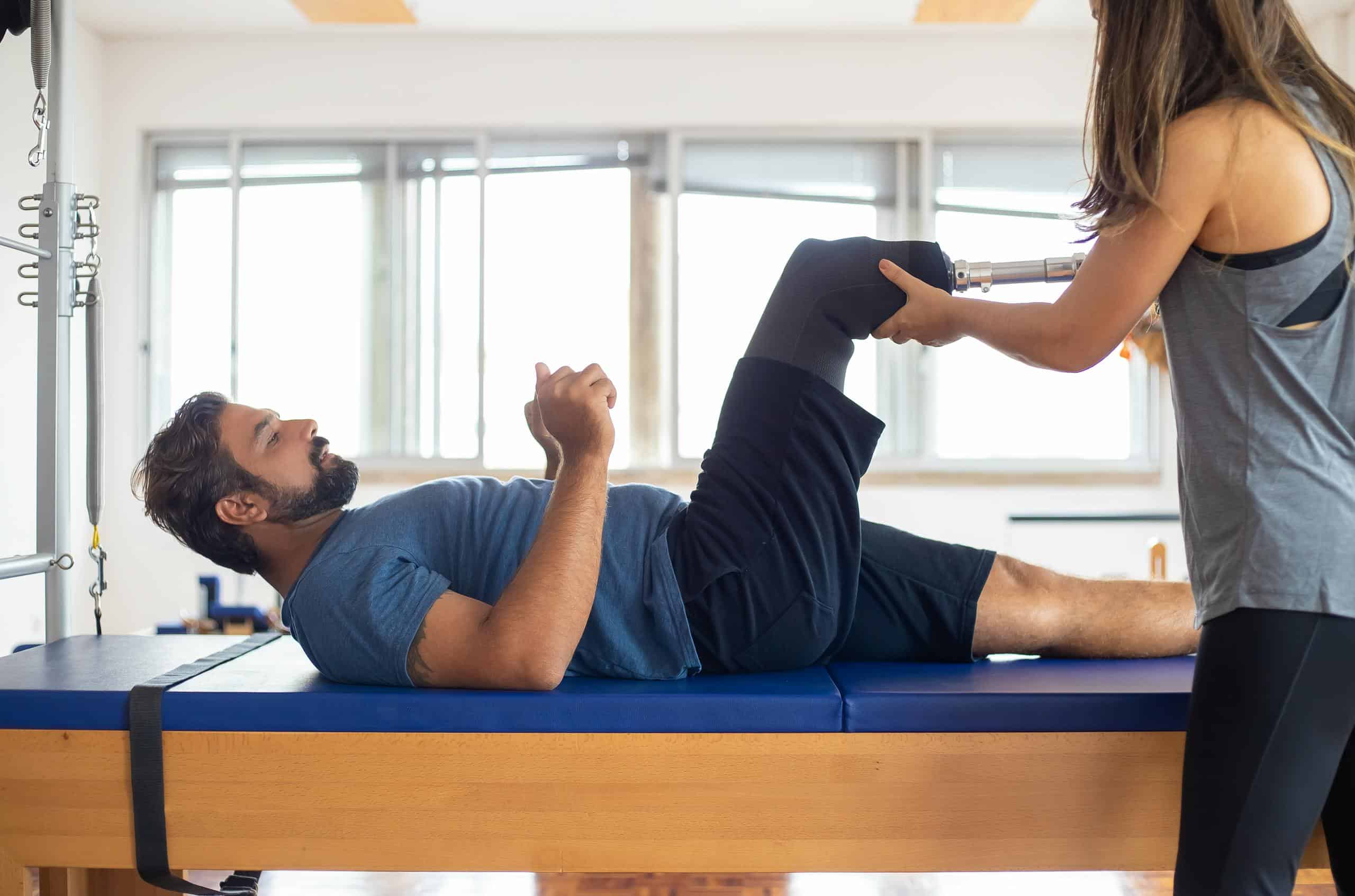 Man and woman engaging in a physical therapy session, focusing on prosthetic leg recovery and injury rehabilitation.